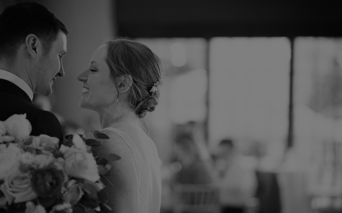 Black and white photo of a bride and groom smiling face to face
