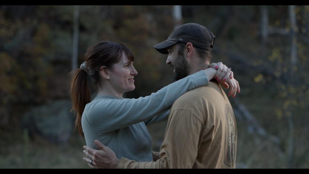 Couple in casual clothes embrace and smile at each other outdoors